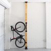 Bicycle installed on a wooden post against a white brick wall.