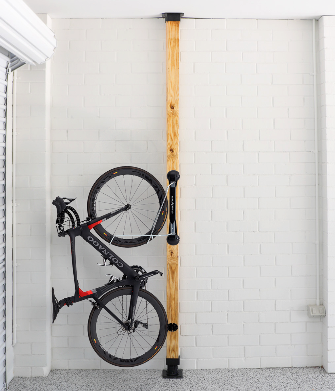 Bicycle hanging on a wooden stand against a white tiled wall.
