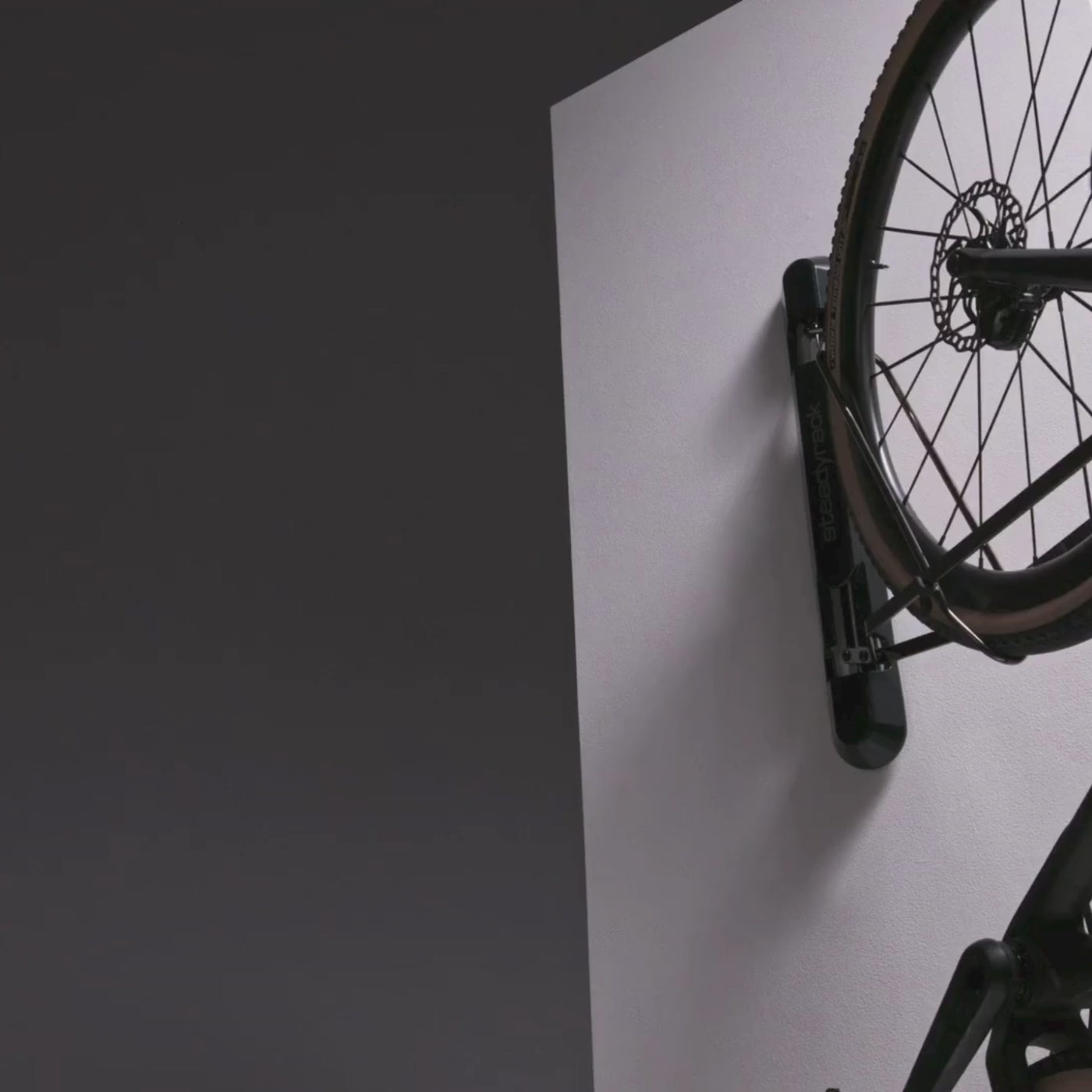 A bike in a black wall mount rack being pivoted to the left